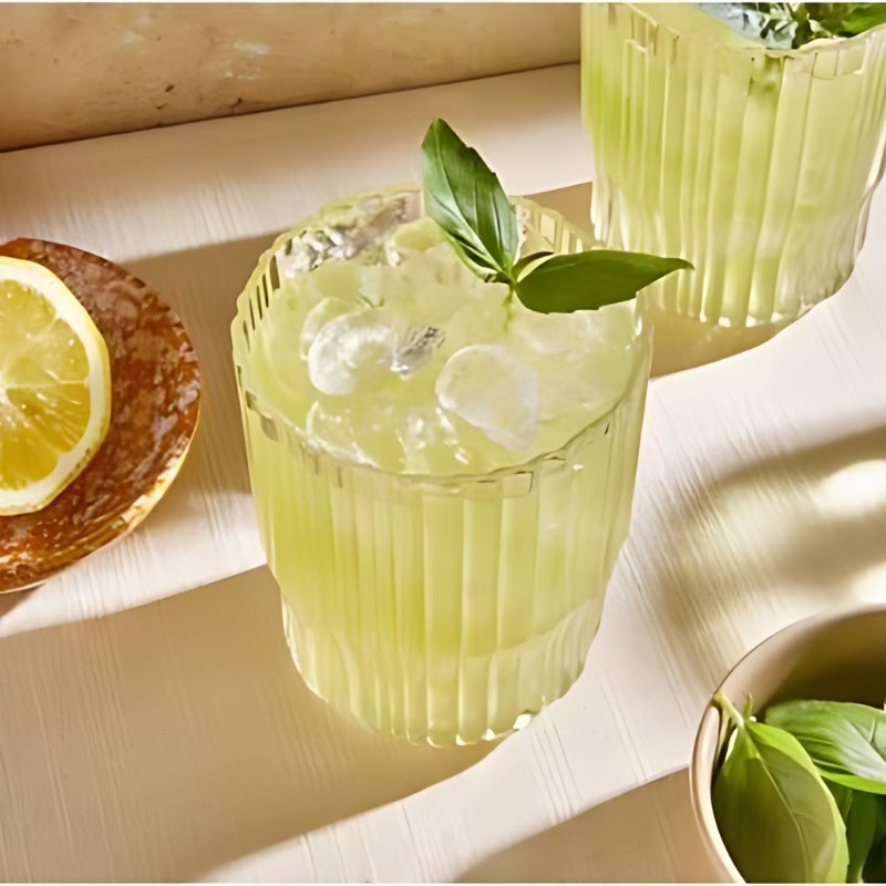Zwei elegante Gläser mit grünem Basilikum-Cocktail auf Eis und Zitronenscheibe – Serviervorschlag für Mampe Gin.
