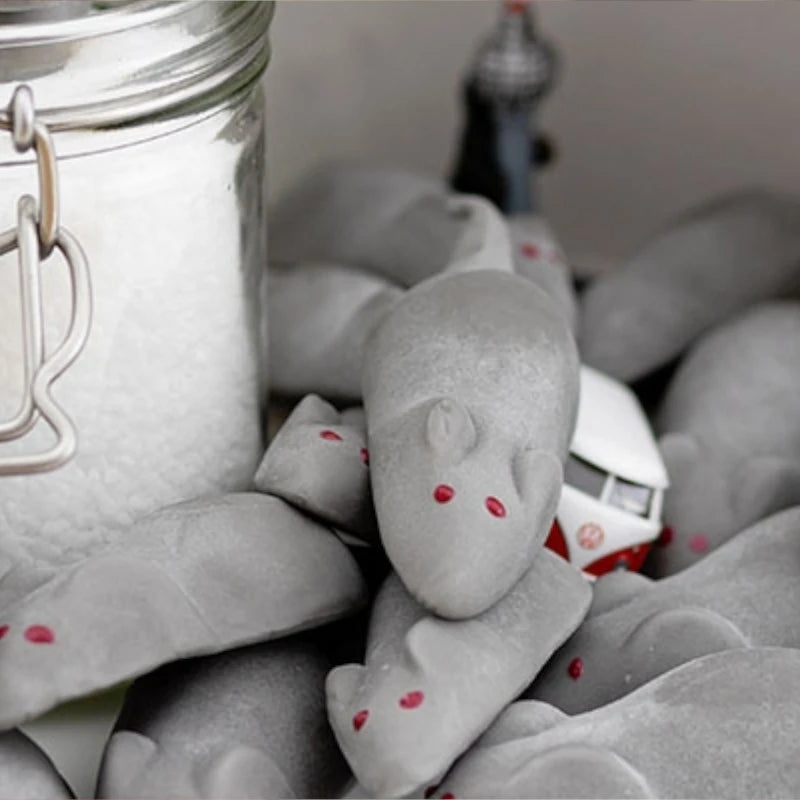 Detailansicht der Aseli Lakritzmäuse mit roten Augen auf grauem Schaumzucker, dekorativ arrangiert neben Berliner Miniaturen und einem Einmachglas.