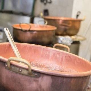 Traditioneller Kupferkessel mit Rührlöffel in einer Berliner Süßwarenmanufaktur während der Zubereitung.