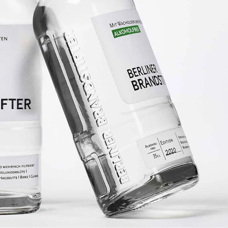 „Zwei alkoholfreie Berliner Brandstifter Flaschen nebeneinander mit eingeprägtem Markenlogo im Glas“