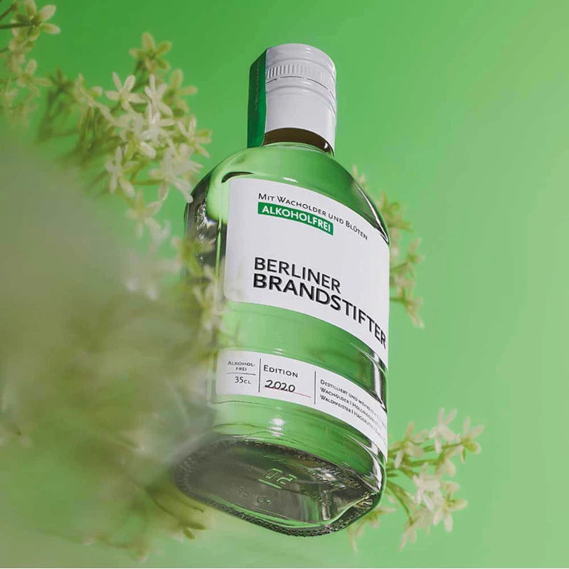 „Berliner Brandstifter alkoholfrei Flasche auf grünem Hintergrund, umgeben von Blüten – Edition 2020“