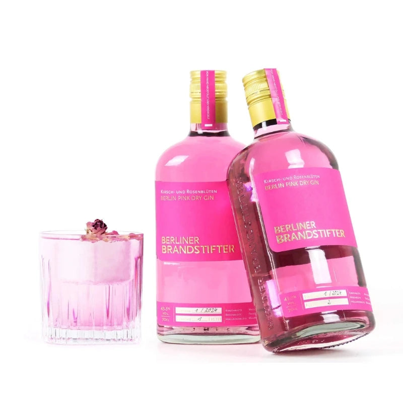 „Zwei Flaschen Berliner Brandstifter Pink Dry Gin neben einem Glas mit pinkem Drink und Trockenblüten – modernes Berliner Gin-Arrangement.“