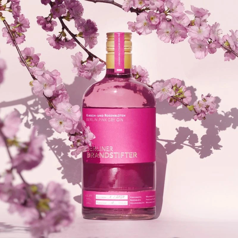 „Flasche Berliner Pink Dry Gin inmitten blühender Kirschblüten – hochwertiger Berliner Gin mit floraler Note.“
