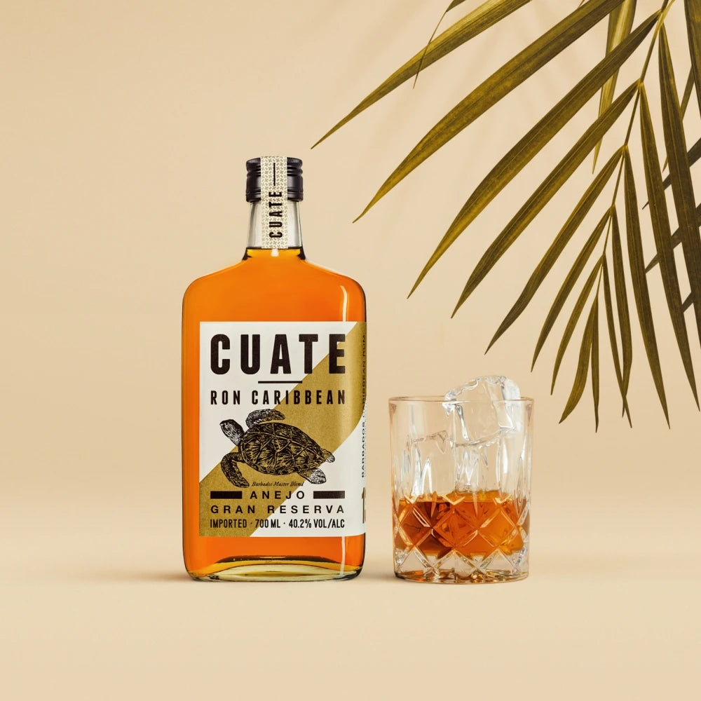 CUATE Rum 13 mit Tumbler-Glas und Eiswürfeln vor tropischem Setting, 700 ml