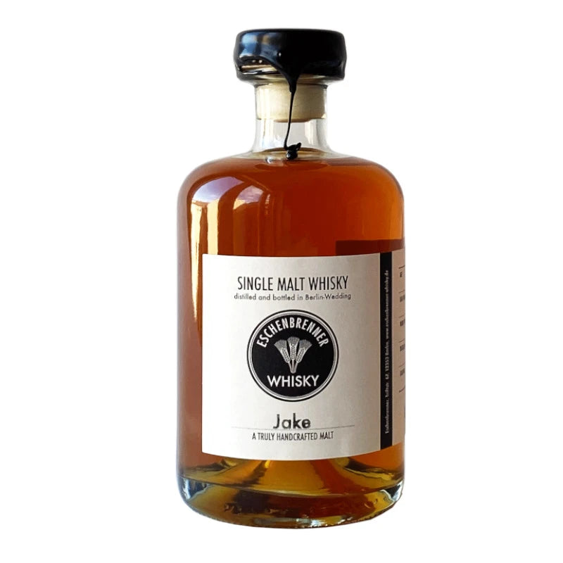 Eschenbrenner Single Malt Whisky „Jake“ in 0,5 l-Flasche mit schwarzem Wachsverschluss. Weißes Etikett mit Logo und Aufschrift „Single Malt Whisky – distilled and bottled in Berlin-Wedding“. Darunter der Name „Jake – A truly handcrafted malt“.