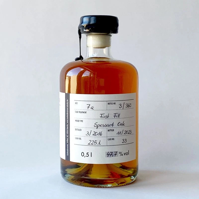 Flasche Eschenbrenner Whisky „Jake“ mit vollständigem Rücketikett und bernsteinfarbener Flüssigkeit. Die Angaben betonen die Handwerkskunst, das Einzelfass und die Herkunft.