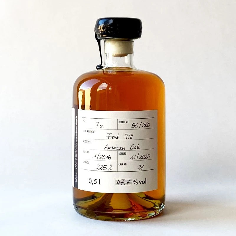 Flasche des Eschenbrenner Whiskys „Quinta“ mit vollständigem Rücketikett in Sicht. Bernsteinfarbener Inhalt, handwerklich gestaltetes Design mit deutlichem Fokus auf Herkunft und Fassdetails.