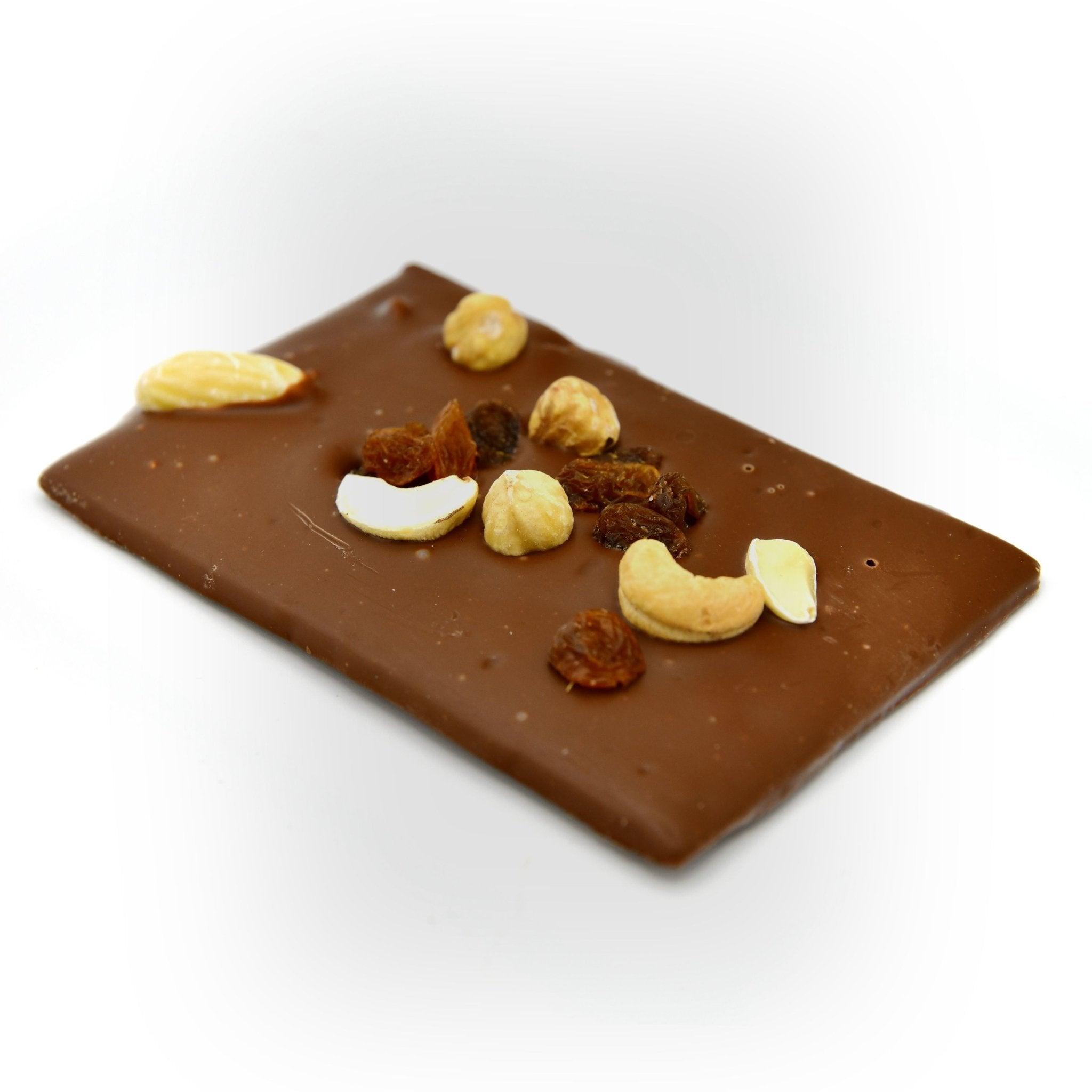Handgegossene Vollmilchschokolade mit gerösteten Nüssen und getrockneten Trauben – diagonale Perspektive, Berliner Manufakturqualität.