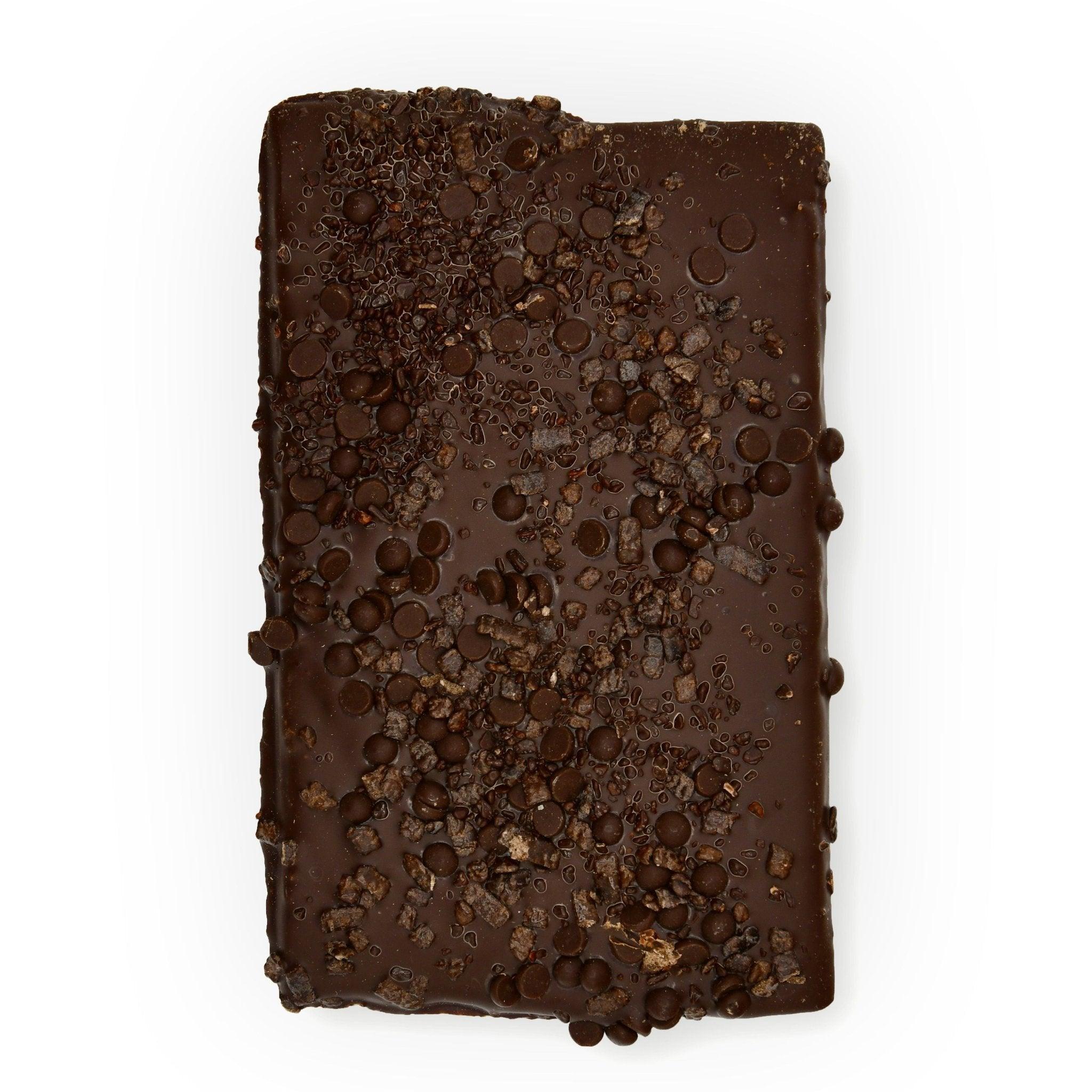 Obenansicht einer dunklen Schokoladentafel mit vielfältigem Schokoladen-Topping – ein Manufakturprodukt aus Berlin für echte Schokofans.