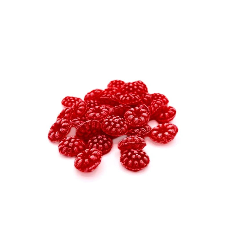 Einzelne rote Himbeerbonbons in Beerenform, lose auf weißem Hintergrund arrangiert.