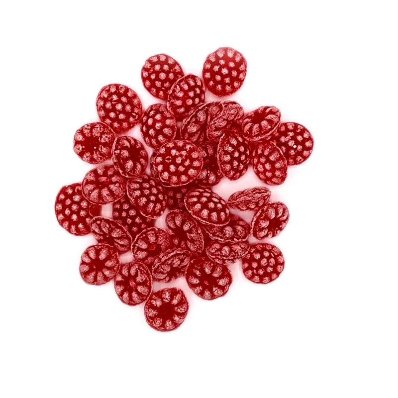 Ansicht von oben: eine größere Menge roter Himbeerbonbons in Beerenform auf weißem Hintergrund verteilt.