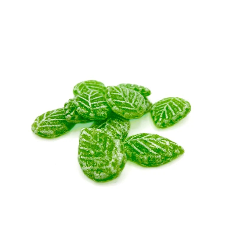 Mehrere grüne Waldmeisterbonbons mit Blattprägung auf weißem Hintergrund, leicht gezuckert und gleichmäßig geformt.