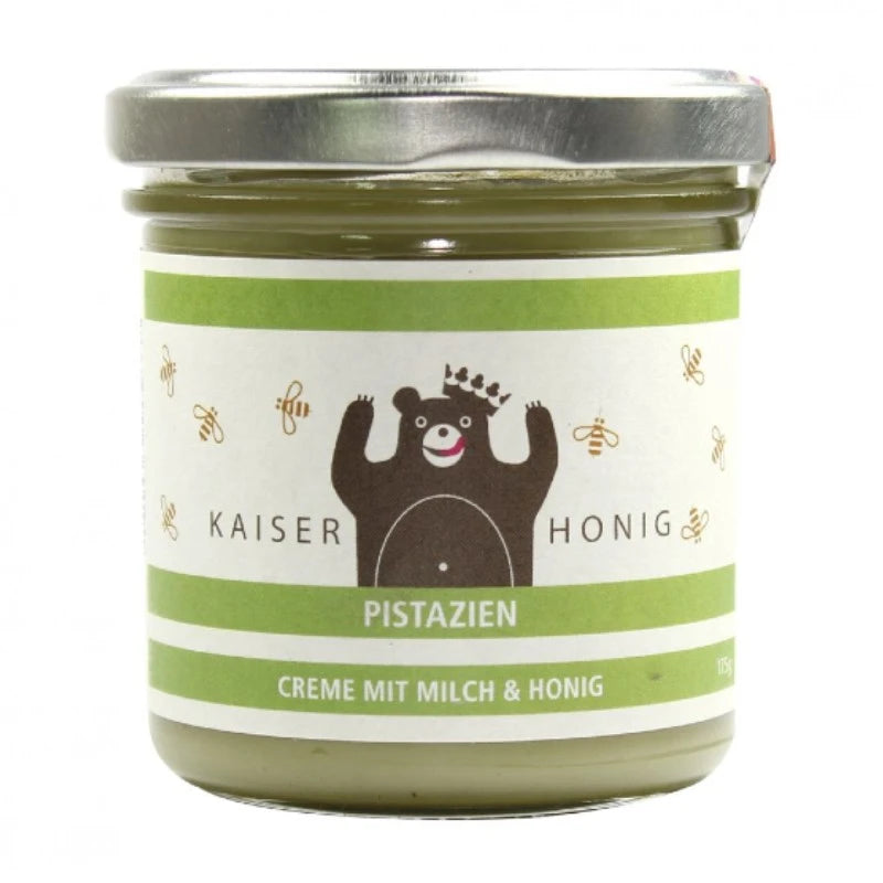 Glas Kaiserhonig Pistaziencreme mit silbernem Deckel, grün-weißem Etikett, Bärenillustration mit Krone und der Aufschrift „Creme mit Milch & Honig“.