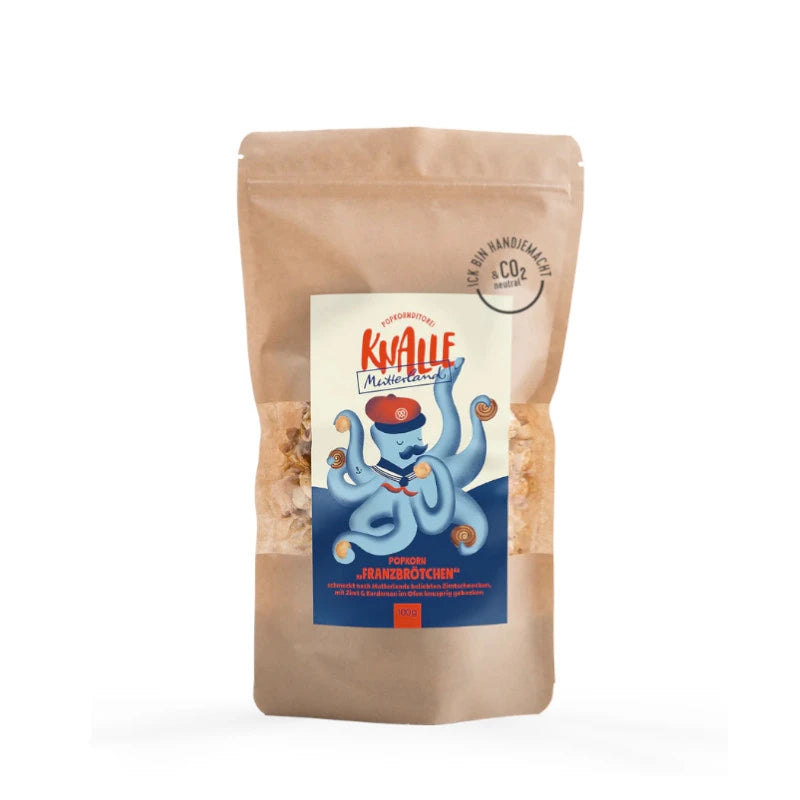 Knalle Popkorn Franzbrötchen, 100 g im braunen Beutel mit verspieltem Etikett: blauer Oktopus mit Zimtrollen-Tentakeln. Popkorn mit Butter-Zimt-Aroma – handgemacht und CO₂-neutral.