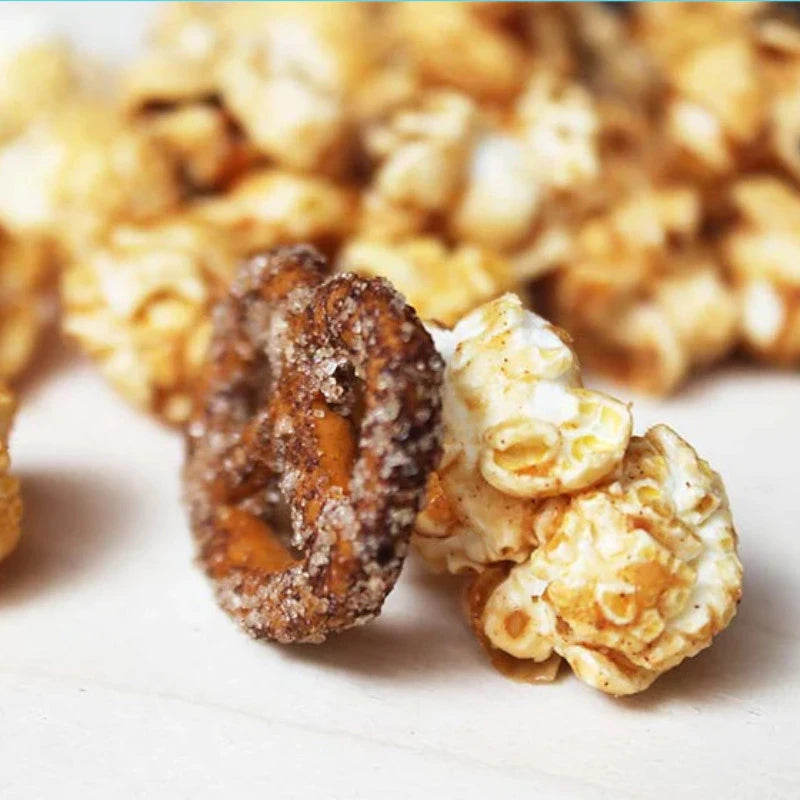 Nahaufnahme von einzelner gesalzener Mini-Brezel mit karamellisiertem Popcorn auf heller Unterlage. Handgemacht in Berlin – ein süß-salziges Highlight.