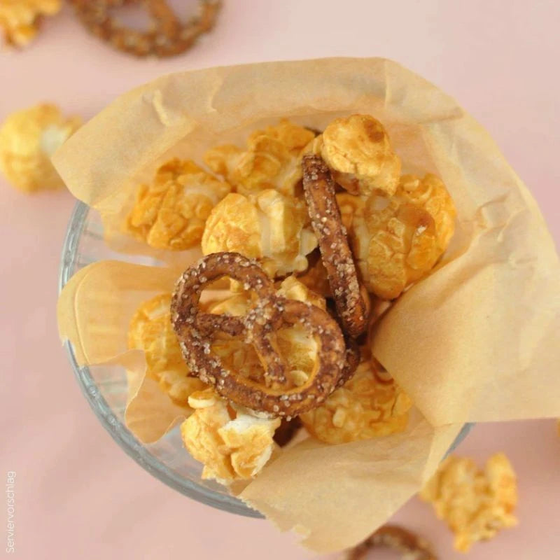 Serviervorschlag: Knalle Popcorn mit Salzbrezeln in einem mit Backpapier ausgelegten Glas. Perfekt zum Teilen – Berliner Snackkultur mit Stil.