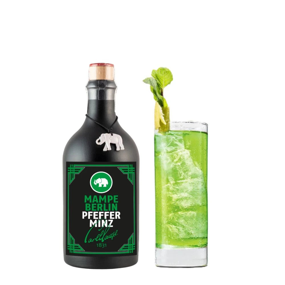 Flasche Mampe Berlin Pfefferminz neben einem Longdrinkglas mit leuchtend grünem Minzcocktail auf Eis, garniert mit Limettenzeste und frischer Minze. Der Drink wirkt frisch, intensiv und sommerlich.