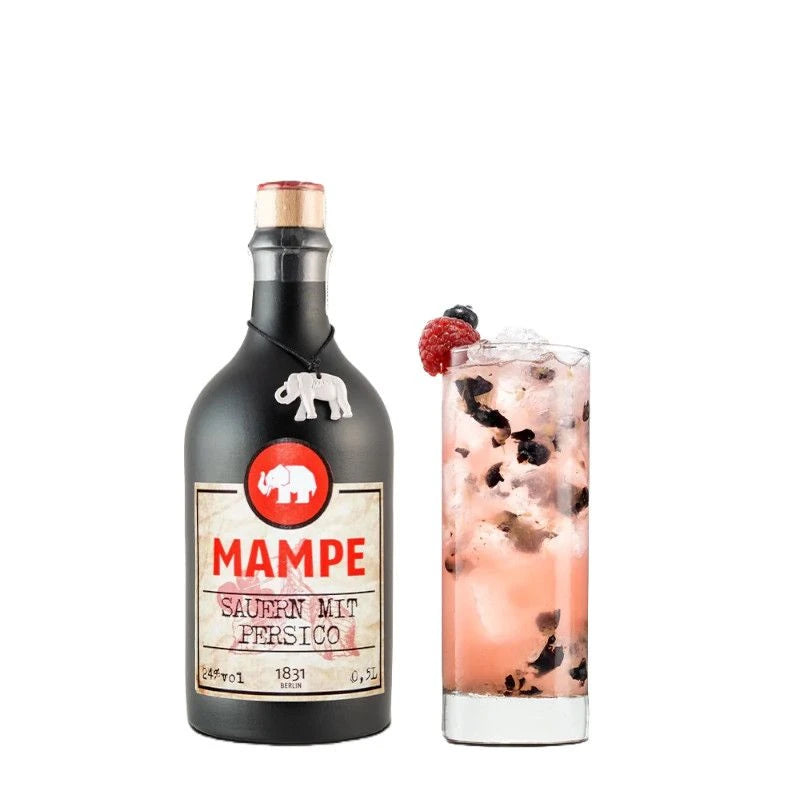 Mampe Sauern mit Persico Flasche neben einem Longdrinkglas mit pinkfarbenem Drink auf Eis, durchzogen von zerdrückten dunklen Beeren und garniert mit Himbeere und Blaubeere.