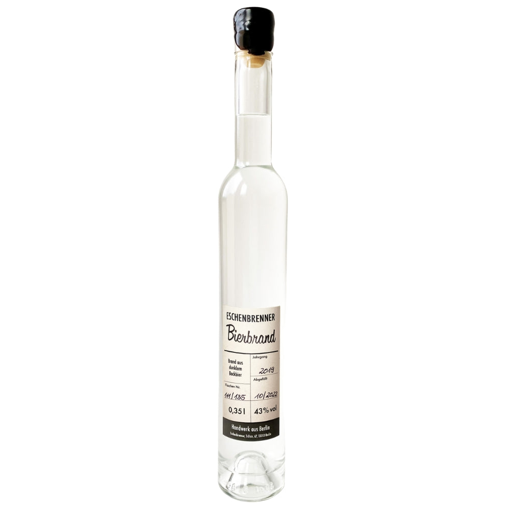 Flasche Eschenbrenner Bierbrand 0,35 l mit schwarzem Wachsverschluss, klarer Spirituose und handbeschriftetem Etikett, stehend vor weißem Hintergrund.