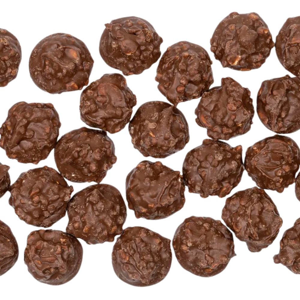Knusprige Vollmilchschokoladen-Cluster mit sichtbaren Nuss- und Karamellstückchen, in unregelmäßiger runder Form auf weißem Hintergrund.