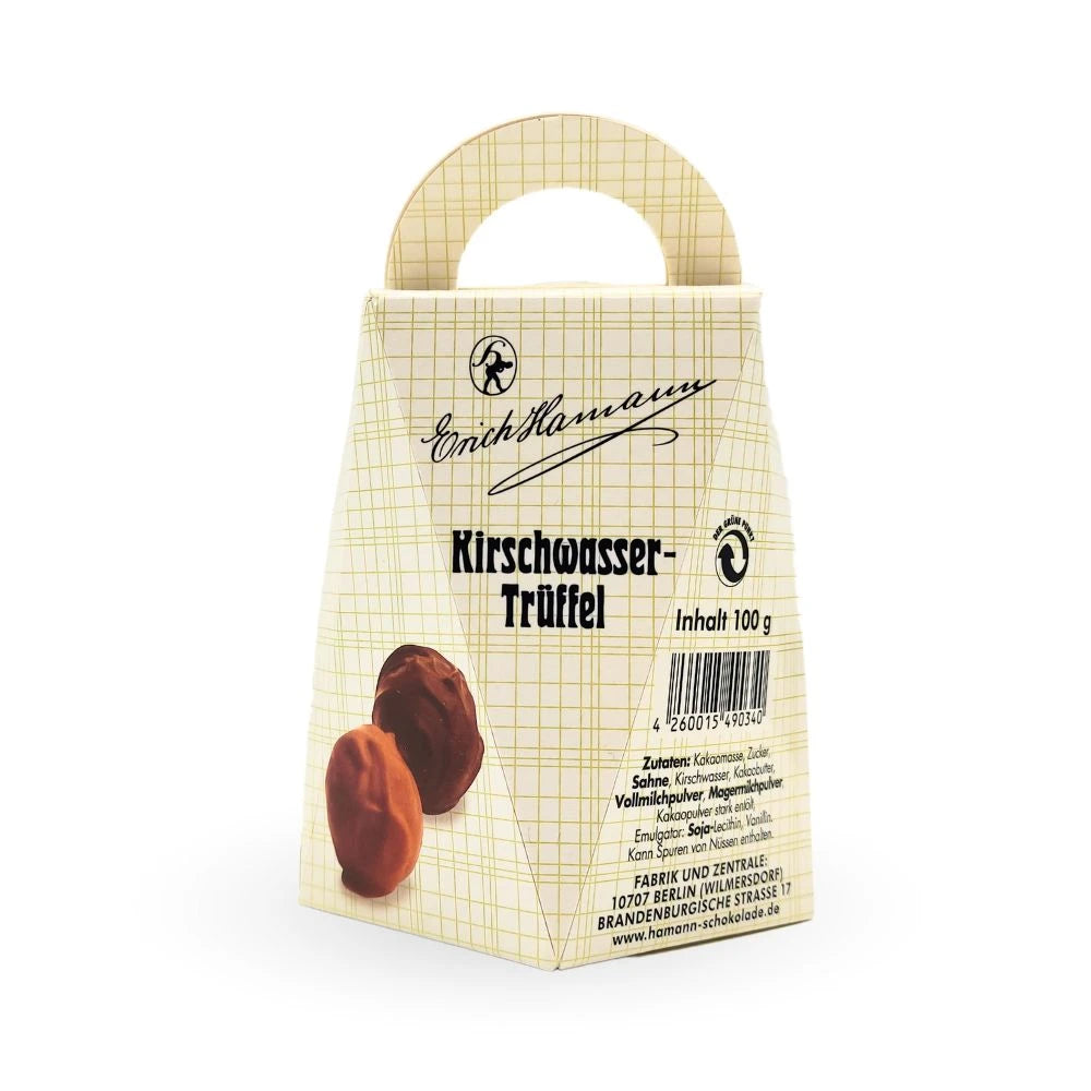 Geschenkschachtel mit Tragegriff von Erich Hamann, beschriftet mit „Kirschwasser-Trüffel“. Klassisches Karomuster in Creme mit roter und schwarzer Schrift, darunter zwei Pralinen abgebildet. Berliner Manufaktur-Design mit Barcode und Zutatenangabe.