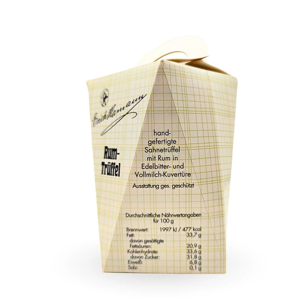 Seitenansicht der Verpackung der Erich Hamann Rum-Trüffel mit Text zur handgefertigten Herstellung in Vollmilch- und Zartbitterkuvertüre sowie einer Nährwerttabelle auf hellem, kariertem Hintergrund.