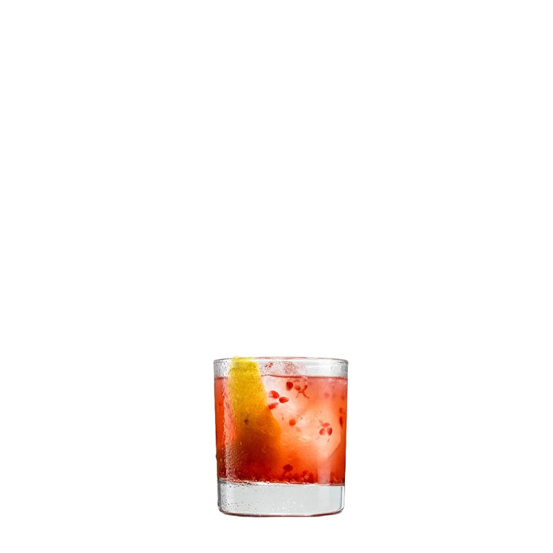 Tumblerglas mit rotem Bittercocktail auf Eis, angereichert mit frischen Himbeerstückchen und einer Zitronenzeste. Der Drink wirkt fruchtig-herb und handgemacht.