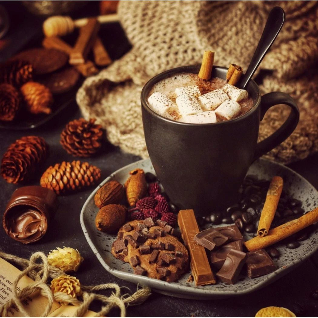 Stimmungsvolles Arrangement mit schwarzer Tasse heißer Schokolade, bestreut mit Marshmallows und Zimt, umgeben von Schokolade, Keksen, Nüssen und herbstlicher Deko.